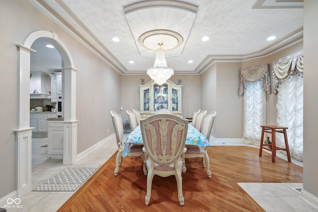 dining room featuring light hardwood / wood-style floors, a notable chandelier, crown molding, and a textured ceiling