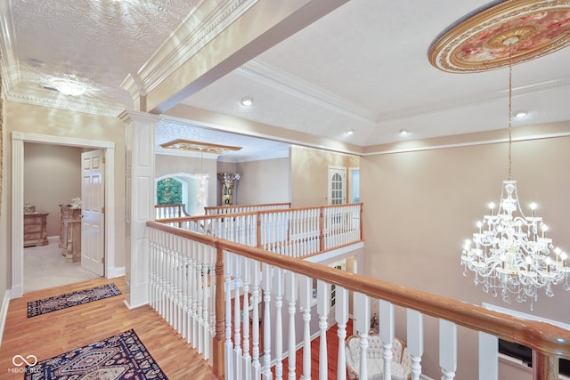 corridor featuring a chandelier, crown molding, a textured ceiling, and hardwood / wood-style flooring