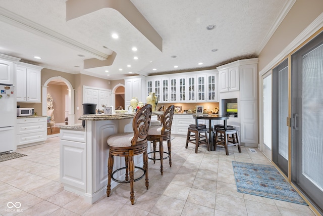 kitchen with white cabinetry, crown molding, white appliances, and a kitchen bar