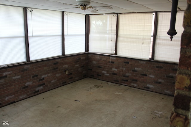 unfurnished sunroom with a drop ceiling and ceiling fan