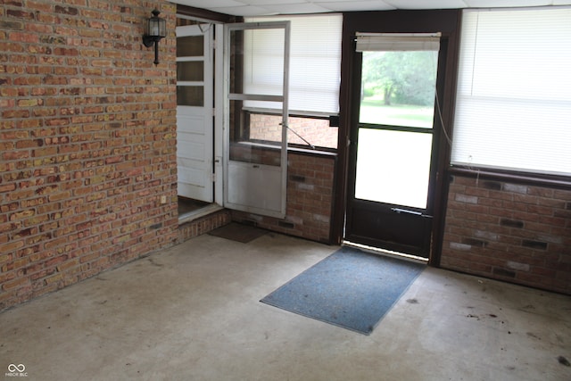 doorway to outside with brick wall and concrete floors