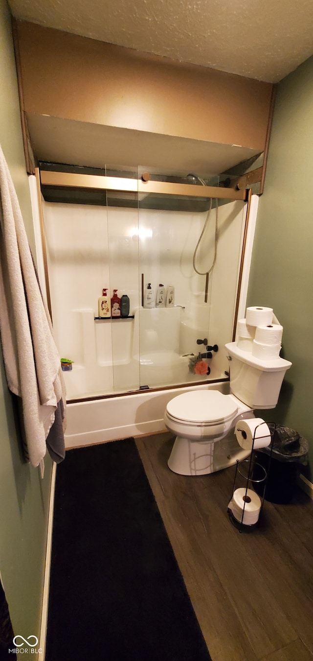 bathroom with shower / bath combination with glass door, hardwood / wood-style floors, toilet, and a textured ceiling