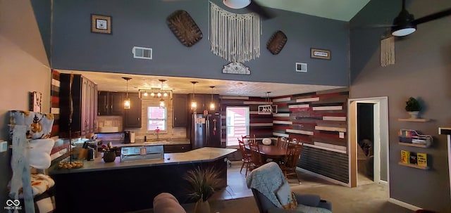 interior space with a towering ceiling, ceiling fan with notable chandelier, and sink