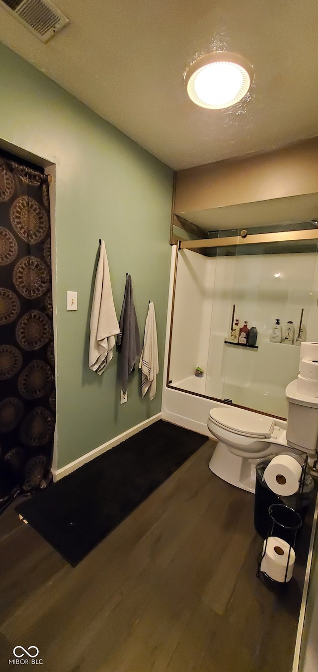 bathroom with hardwood / wood-style flooring, a shower, and toilet