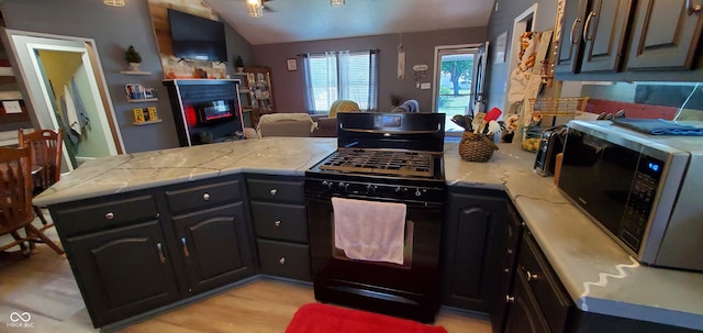 kitchen with gas range oven, vaulted ceiling, light hardwood / wood-style flooring, and kitchen peninsula