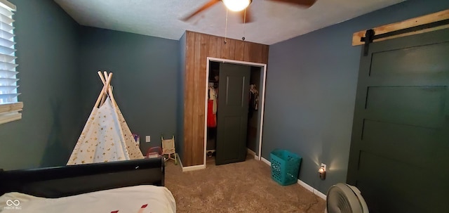 bedroom with carpet, a barn door, and ceiling fan