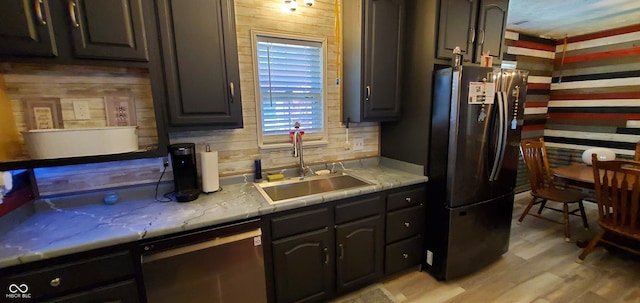 kitchen with black refrigerator, sink, stainless steel dishwasher, and light hardwood / wood-style floors