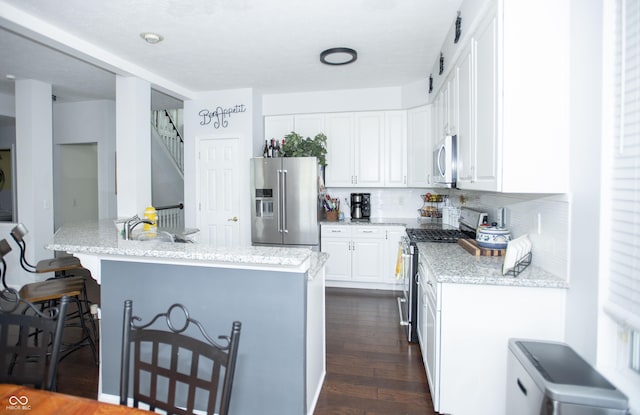 kitchen with stainless steel appliances, sink, white cabinets, decorative backsplash, and dark hardwood / wood-style flooring