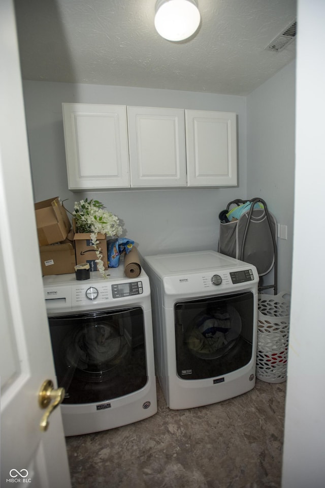 clothes washing area with cabinets and washer and clothes dryer