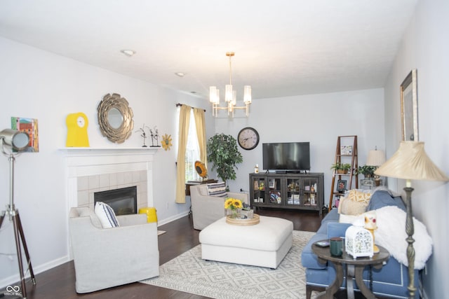 living room featuring a tiled fireplace, a chandelier, and hardwood / wood-style floors