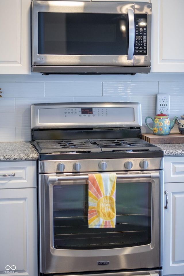 kitchen featuring white cabinets, tasteful backsplash, and appliances with stainless steel finishes