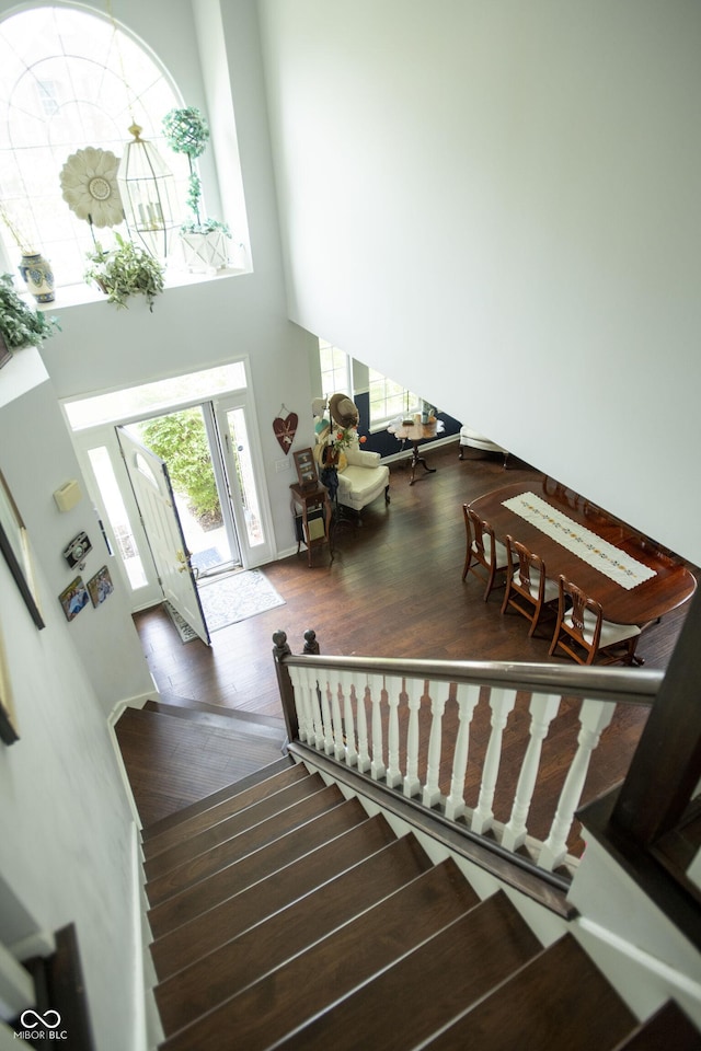 staircase featuring a towering ceiling and wood-type flooring