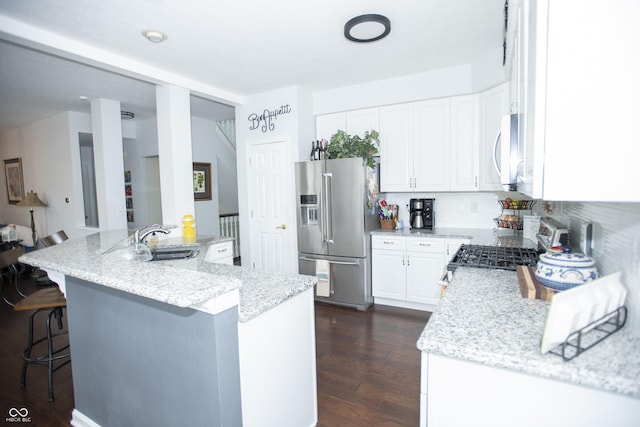 kitchen featuring light stone countertops, a center island with sink, white cabinetry, high quality fridge, and sink