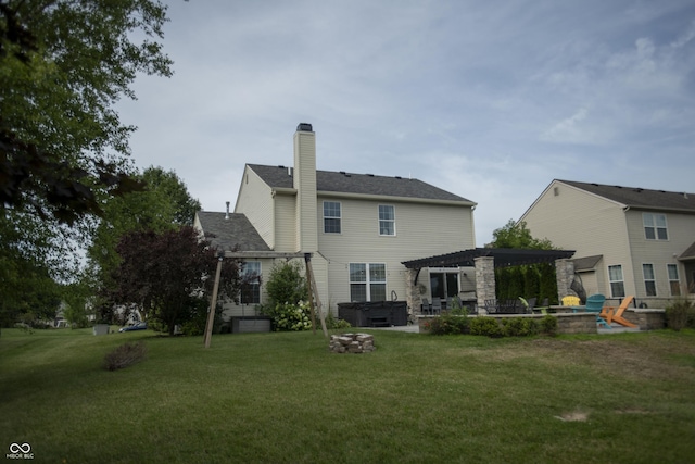 back of property featuring a patio, a fire pit, a hot tub, a yard, and a pergola