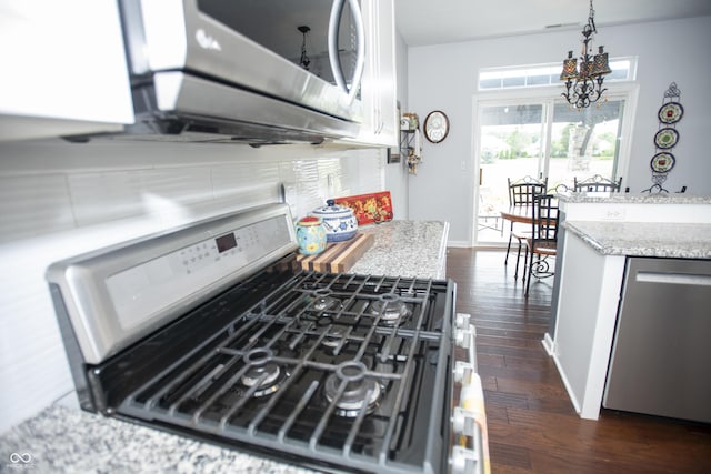 kitchen with appliances with stainless steel finishes, dark wood-type flooring, light stone counters, and decorative backsplash