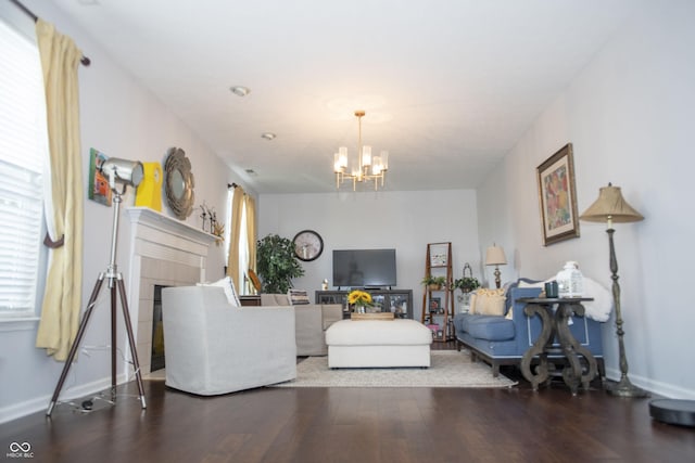 living room featuring a notable chandelier, a tile fireplace, and wood-type flooring