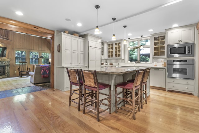 kitchen with pendant lighting, a kitchen breakfast bar, stainless steel appliances, a center island, and light stone countertops