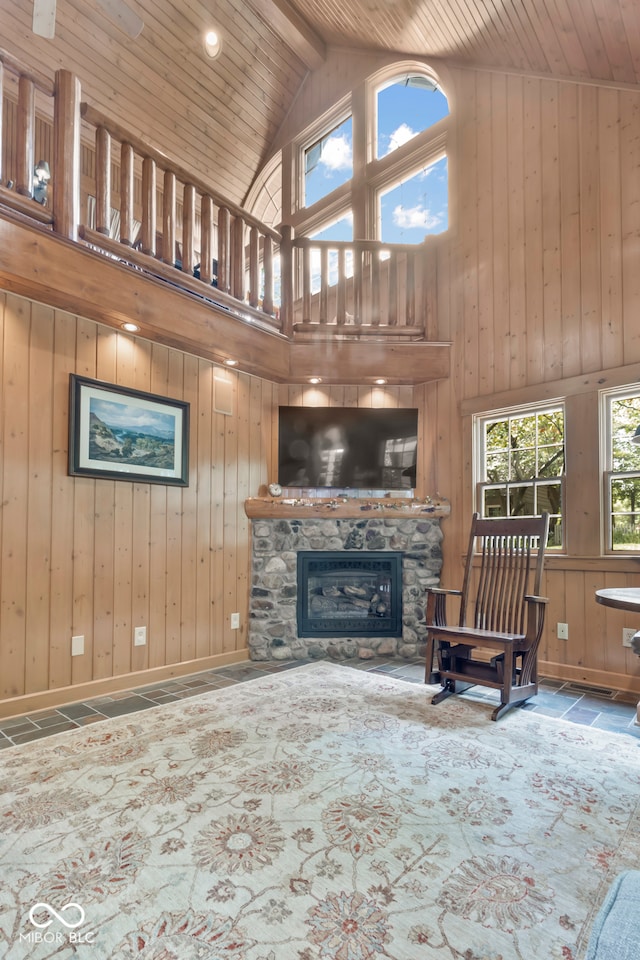 unfurnished living room with high vaulted ceiling, wooden ceiling, a fireplace, and wood walls