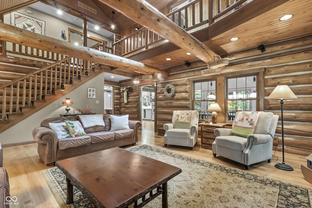 living room featuring beam ceiling, a towering ceiling, wooden ceiling, and light wood-type flooring