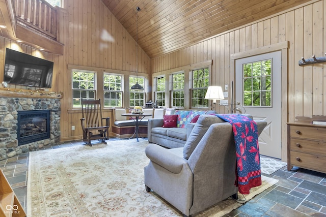 living room with wood ceiling, a fireplace, high vaulted ceiling, and wood walls