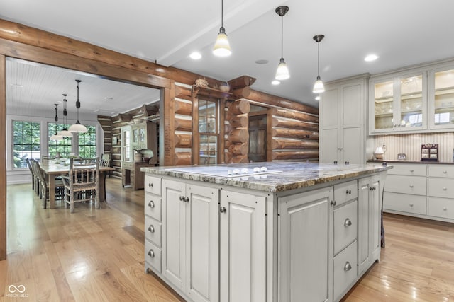 kitchen with decorative light fixtures, light hardwood / wood-style flooring, log walls, and a kitchen island