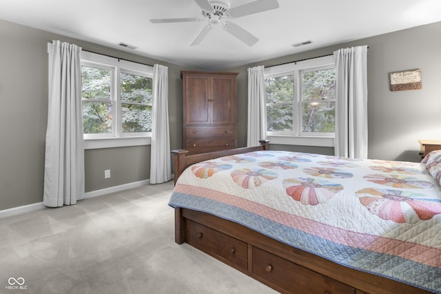 bedroom featuring light carpet, multiple windows, and ceiling fan