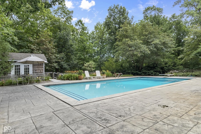 view of pool with a diving board and a patio