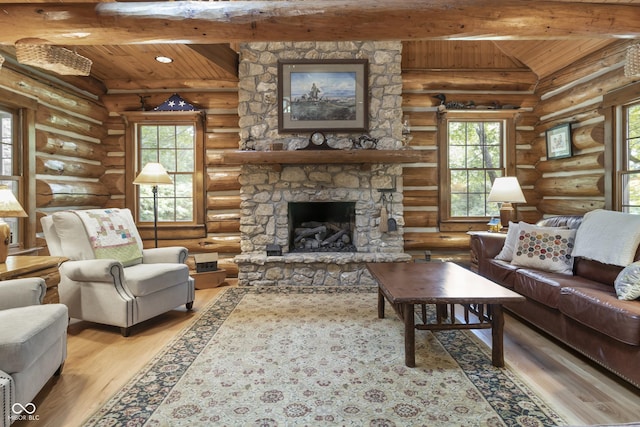 living room with a stone fireplace, light hardwood / wood-style flooring, lofted ceiling with beams, and plenty of natural light