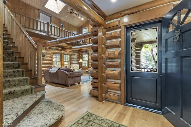 foyer with beam ceiling, a skylight, high vaulted ceiling, and light wood-type flooring