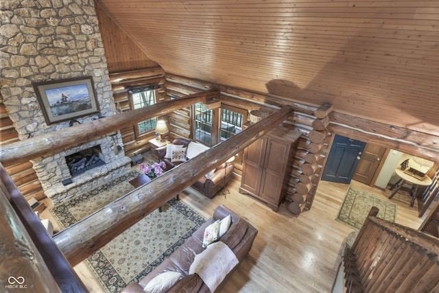 living room with wood ceiling, a stone fireplace, high vaulted ceiling, and light wood-type flooring