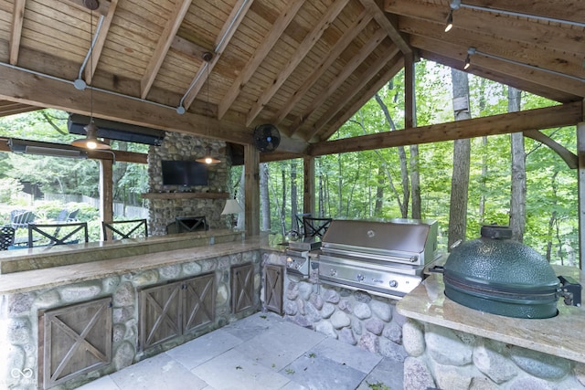 view of patio / terrace with area for grilling, a gazebo, an outdoor stone fireplace, and an outdoor kitchen