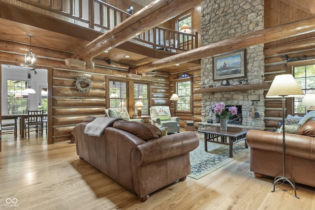 living room with a towering ceiling, a wealth of natural light, a fireplace, and light hardwood / wood-style flooring