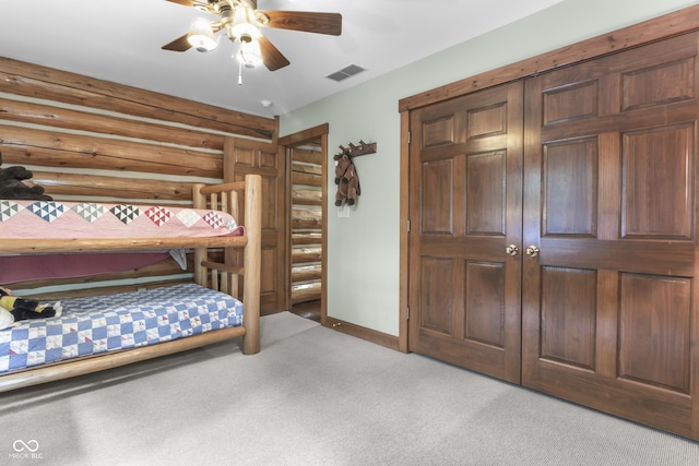 bedroom featuring light carpet, rustic walls, ceiling fan, and a closet