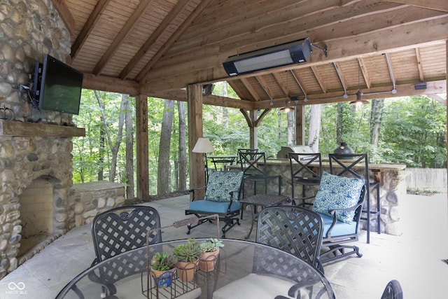 view of patio featuring a gazebo, exterior bar, and an outdoor stone fireplace