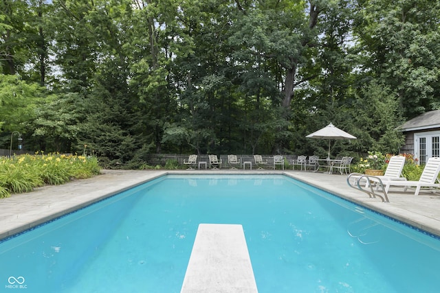 view of swimming pool featuring a patio and a diving board