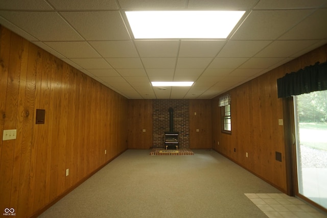 basement with wood walls, a healthy amount of sunlight, and a wood stove