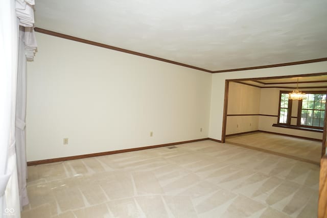 spare room featuring crown molding, light colored carpet, and a chandelier