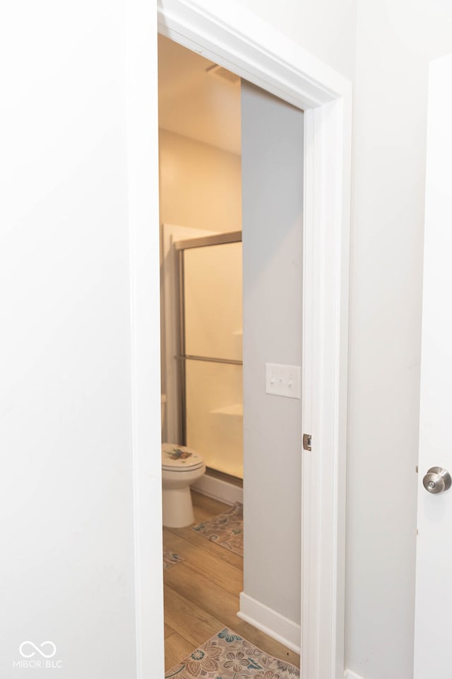 bathroom featuring wood-type flooring, a baseboard radiator, toilet, and an enclosed shower