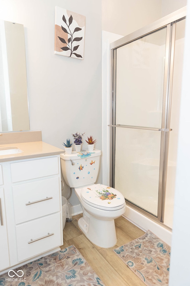 bathroom with hardwood / wood-style floors, vanity, toilet, and a shower with door