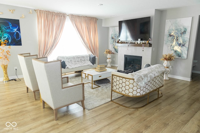 living room with wood-type flooring and a tiled fireplace