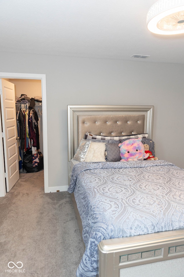 bedroom with a spacious closet, light carpet, and a closet