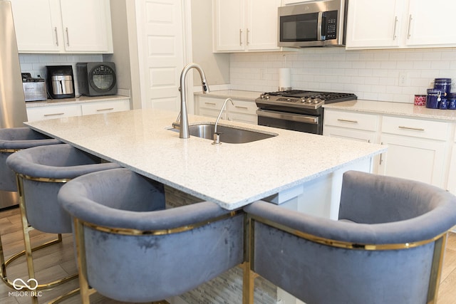 kitchen featuring appliances with stainless steel finishes, backsplash, light hardwood / wood-style flooring, and white cabinets