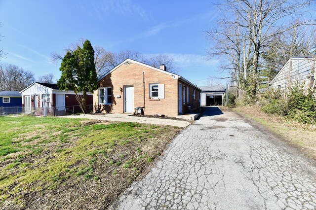 3612 Schofield Ave, Indianapolis, IN 46218 - bungalow with driveway, fence, a front yard, brick siding, and a chimney