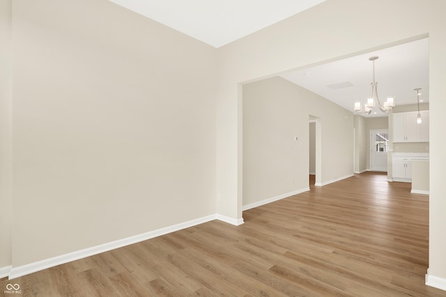 unfurnished room featuring an inviting chandelier and light wood-type flooring