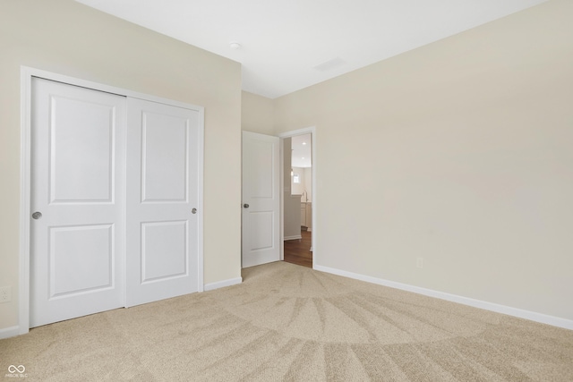 unfurnished bedroom with light colored carpet and a closet