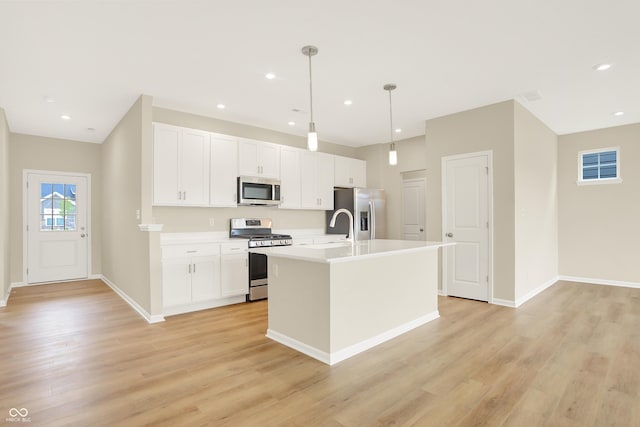 kitchen featuring light hardwood / wood-style flooring, decorative light fixtures, stainless steel appliances, a center island with sink, and white cabinets