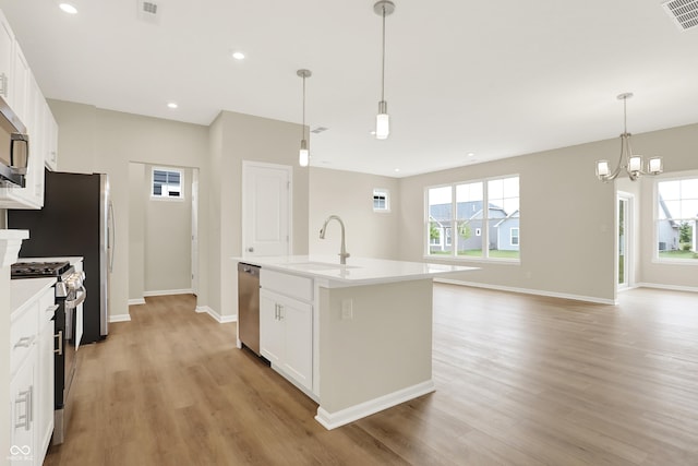 kitchen featuring appliances with stainless steel finishes, hanging light fixtures, white cabinets, and a kitchen island with sink