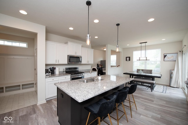6748 Fallen Leaf Dr, Whitestown, IN 46075 - kitchen with appliances with stainless steel finishes, a sink, light wood finished floors, white cabinetry, and a kitchen island with sink