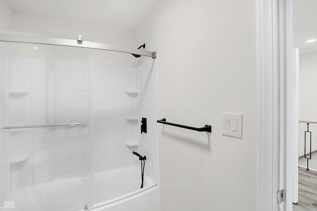 bathroom with hardwood / wood-style flooring and combined bath / shower with glass door