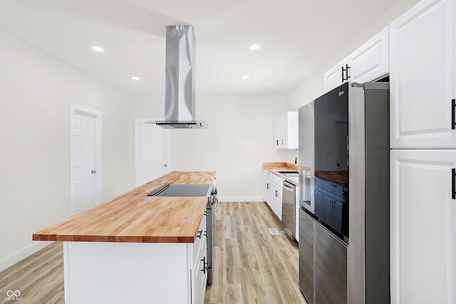 kitchen with appliances with stainless steel finishes, wood counters, white cabinetry, light hardwood / wood-style flooring, and range hood